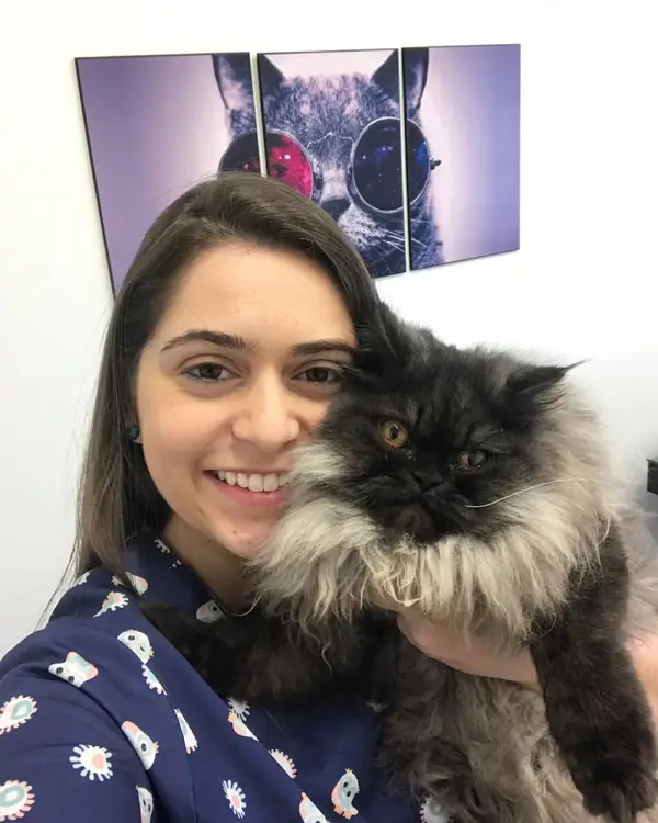 Dra. Laís Rosseto sorrindo ao lado de um gato persa preto e cinza